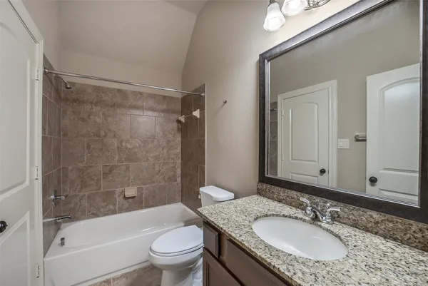 a bathroom with a granite countertop sink toilet mirror and shower