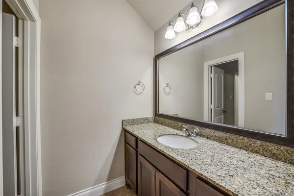a bathroom with a granite countertop sink and a mirror