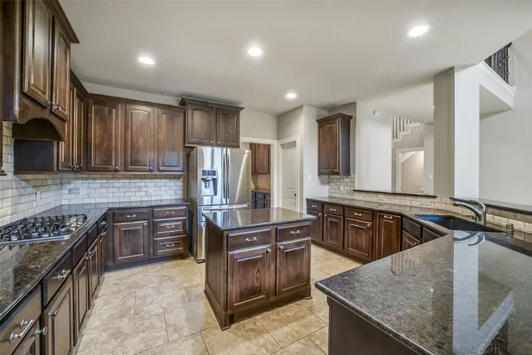 a kitchen with kitchen island granite countertop wooden cabinets and stainless steel appliances