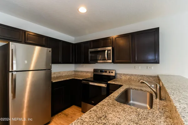 a kitchen with stainless steel appliances granite countertop a refrigerator a stove a sink and a microwave