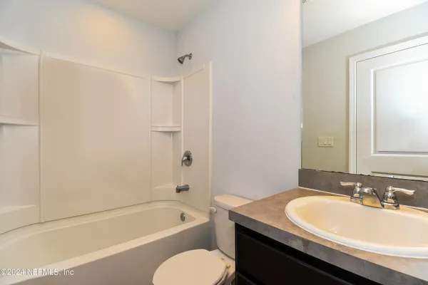 a bathroom with a granite countertop sink toilet mirror and a bathtub