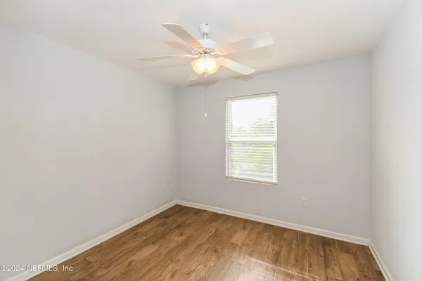 an empty room with a window and a fan