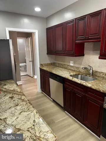 a kitchen with granite countertop wooden cabinets a sink and dishwasher