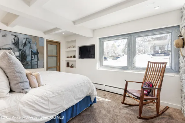 a bedroom with a bed a chair and a large window