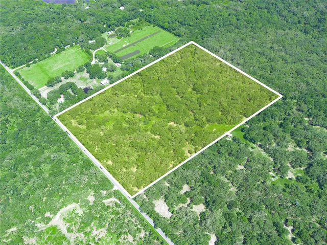 an aerial view of residential house with outdoor space and trees all around