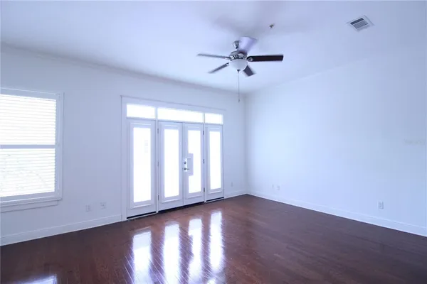 a view of an empty room with wooden floor and a window