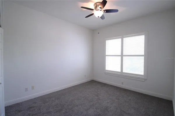 an empty room with a window and a fan