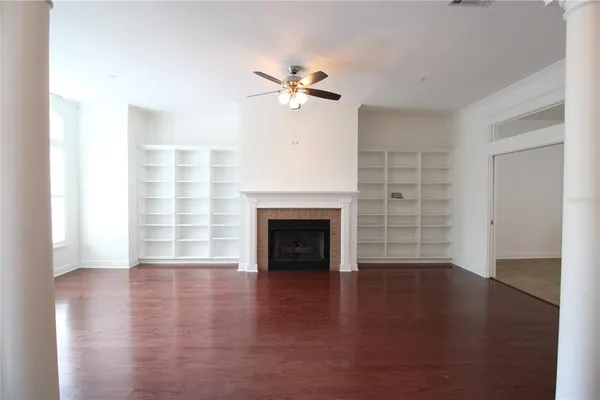 a view of a livingroom with a fireplace a ceiling fan and windows