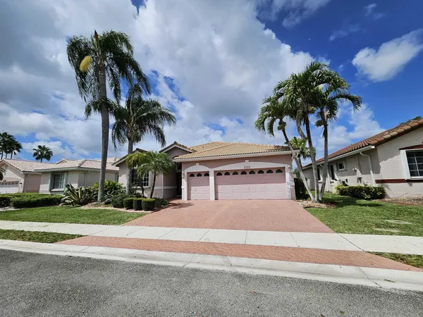 a view of a house with a yard and palm trees