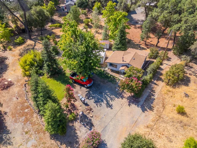 an aerial view of a house with a yard and trees all around