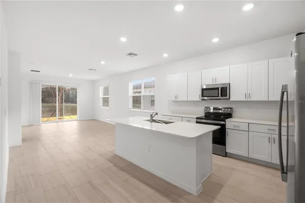 a kitchen with a refrigerator a stove top oven a sink and cabinets