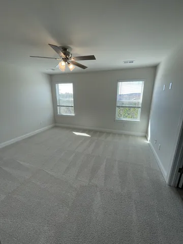 an empty room with windows and ceiling fan