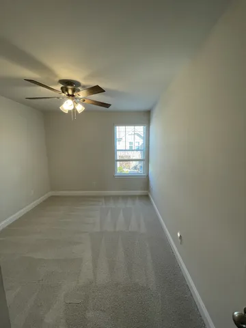 en empty room with windows and chandelier fan