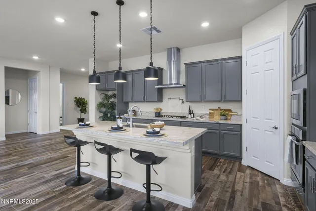 a kitchen with stainless steel appliances granite countertop a sink a stove a refrigerator and island with wooden floor