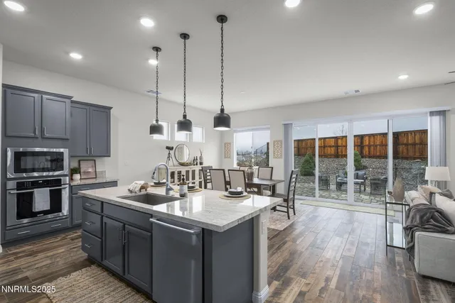 a kitchen with kitchen island a large counter top space a sink appliances and living room view