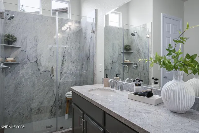 a bathroom with a granite countertop sink a mirror and shower