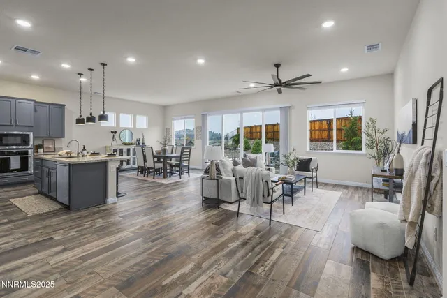 a open kitchen with stainless steel appliances granite countertop a stove oven a dining table and chairs with wooden floor