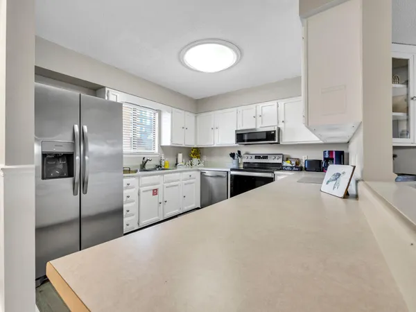 a living room with stainless steel appliances kitchen island a table and chairs in it
