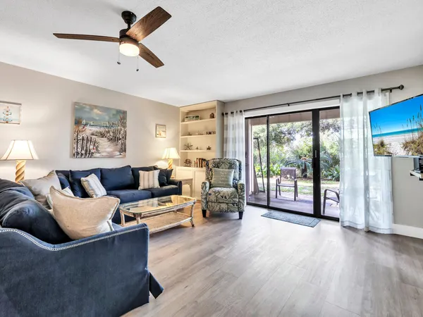 a living room with furniture large window and wooden floor