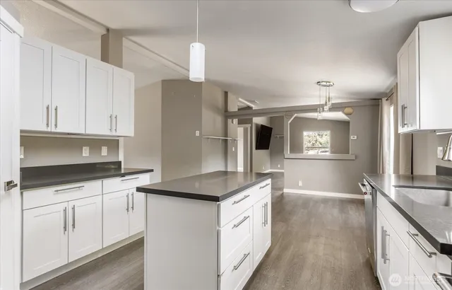 a kitchen with granite countertop a sink and cabinets with wooden floor