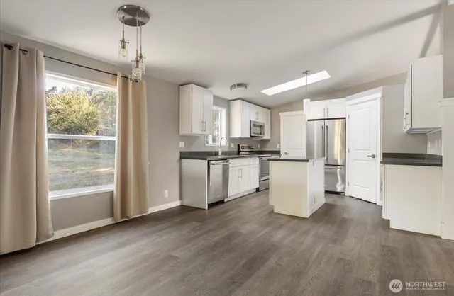 a kitchen with a refrigerator a stove a microwave and white cabinets with wooden floor