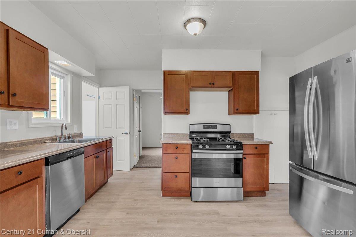 5580 South Merriman Road Wayne, MI 48184 - Photo 6 of 31 Kitchen featuring wood cabinetry, stainless steel appliances, light-toned countertops, a gas range, and wood-finish flooring