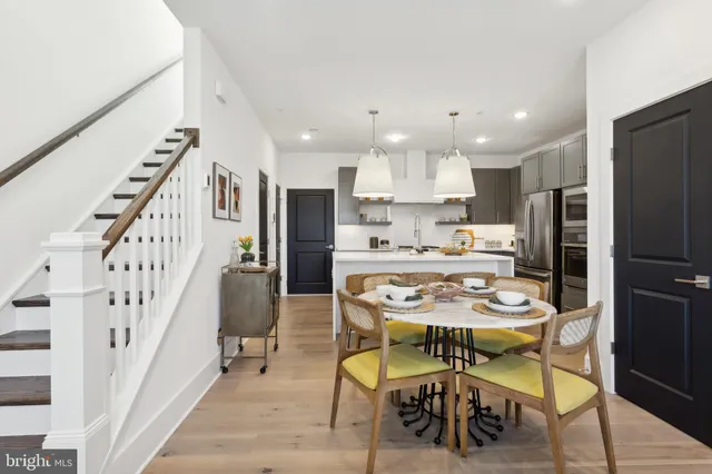 a dining room with stainless steel appliances kitchen island granite countertop a dining table chairs and a refrigerator