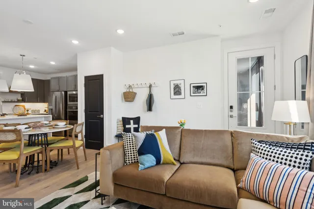 a living room with furniture kitchen view and a wooden floor