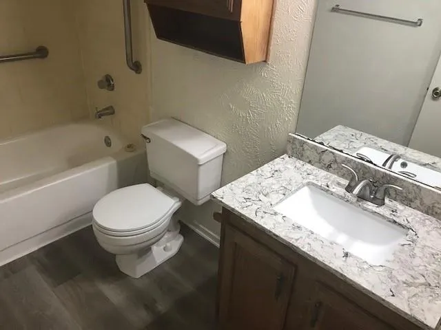 a bathroom with a granite countertop toilet sink and mirror
