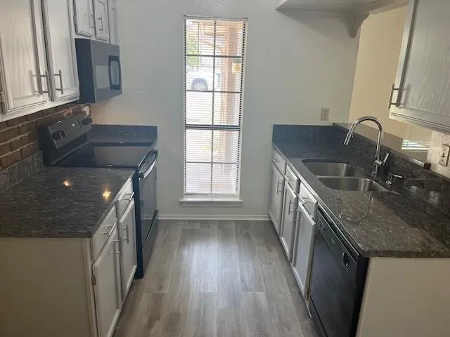 a kitchen with granite countertop a sink stove and cabinets