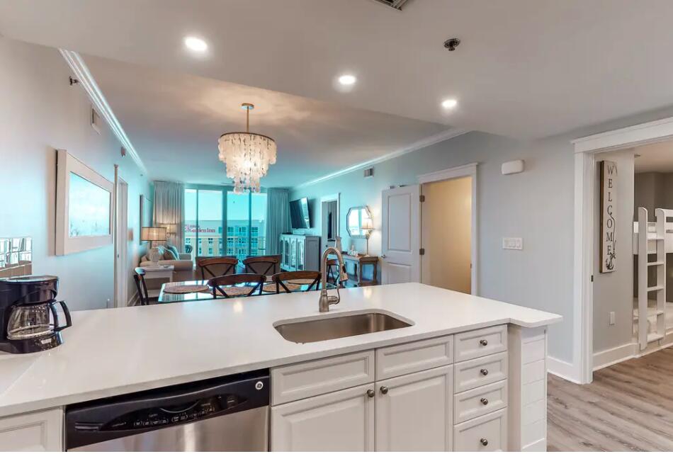 a kitchen with a sink dishwasher a dining table and chairs with wooden floor