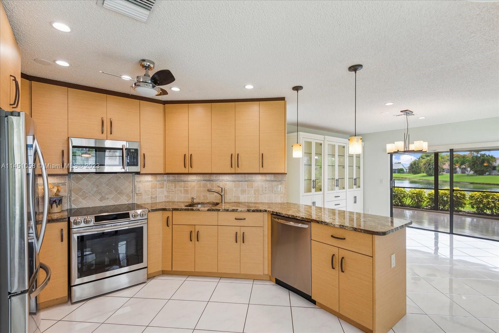 9757 Majorca Place Boca Raton, FL 33434 - Photo 6 of 26 a large kitchen with stainless steel appliances granite countertop a stove a sink and a microwave