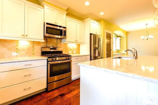 a kitchen with stainless steel appliances granite countertop a sink a stove and a refrigerator