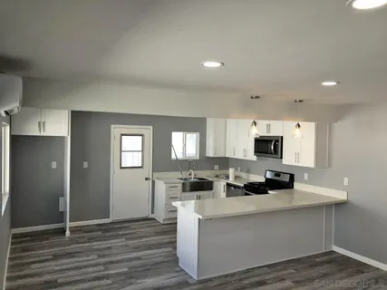 a kitchen with stainless steel appliances a stove a sink cabinets and a wooden floor
