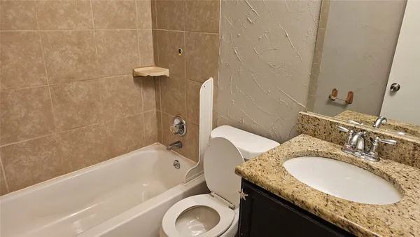 a bathroom with a granite countertop sink a toilet and bathtub