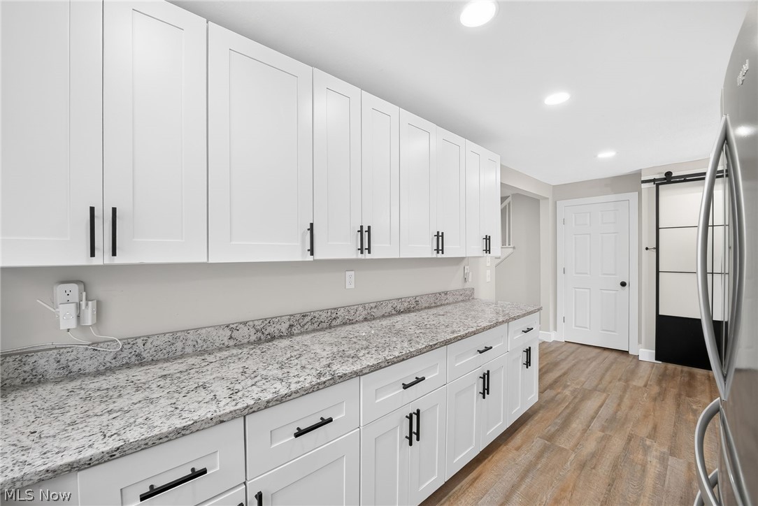 4824 Manchester Road Akron, OH 44319 - Photo 6 of 39 Kitchen featuring extensive white shaker cabinetry with matte black hardware, speckled countertops, wood-finish flooring, and recessed lighting