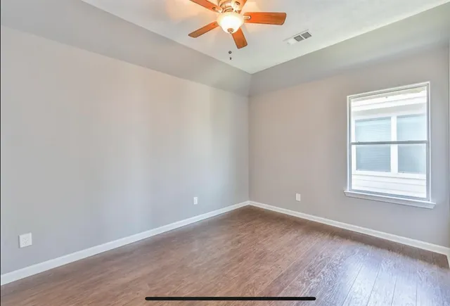 an empty room with wooden floor and windows