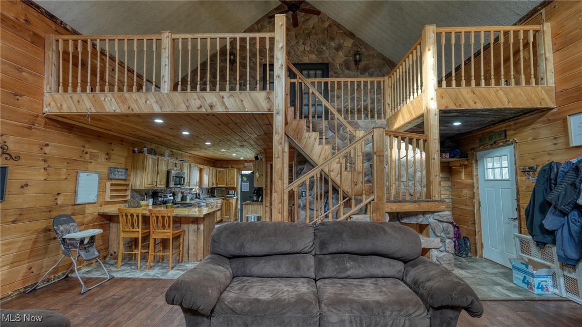 8498 Euga Road Newcomerstown, OH 43832 - Photo 6 of 49 Living room featuring wood walls, high vaulted ceiling, hardwood / wood-style flooring, stairs, and recessed lighting