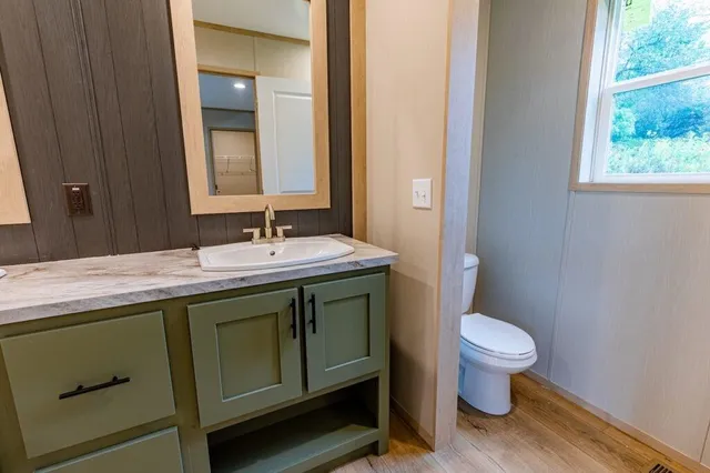 a bathroom with a granite countertop toilet a sink and a mirror