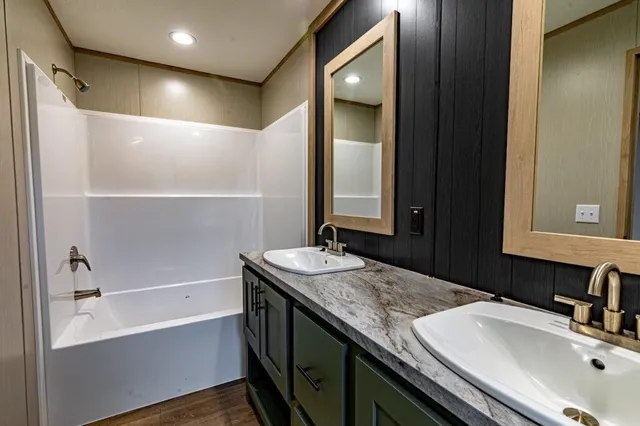 a bathroom with a granite countertop sink a mirror and a bathtub