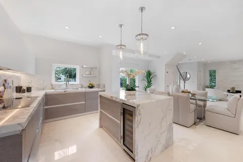 a large kitchen with kitchen island a large counter space a sink a stove and a chandelier