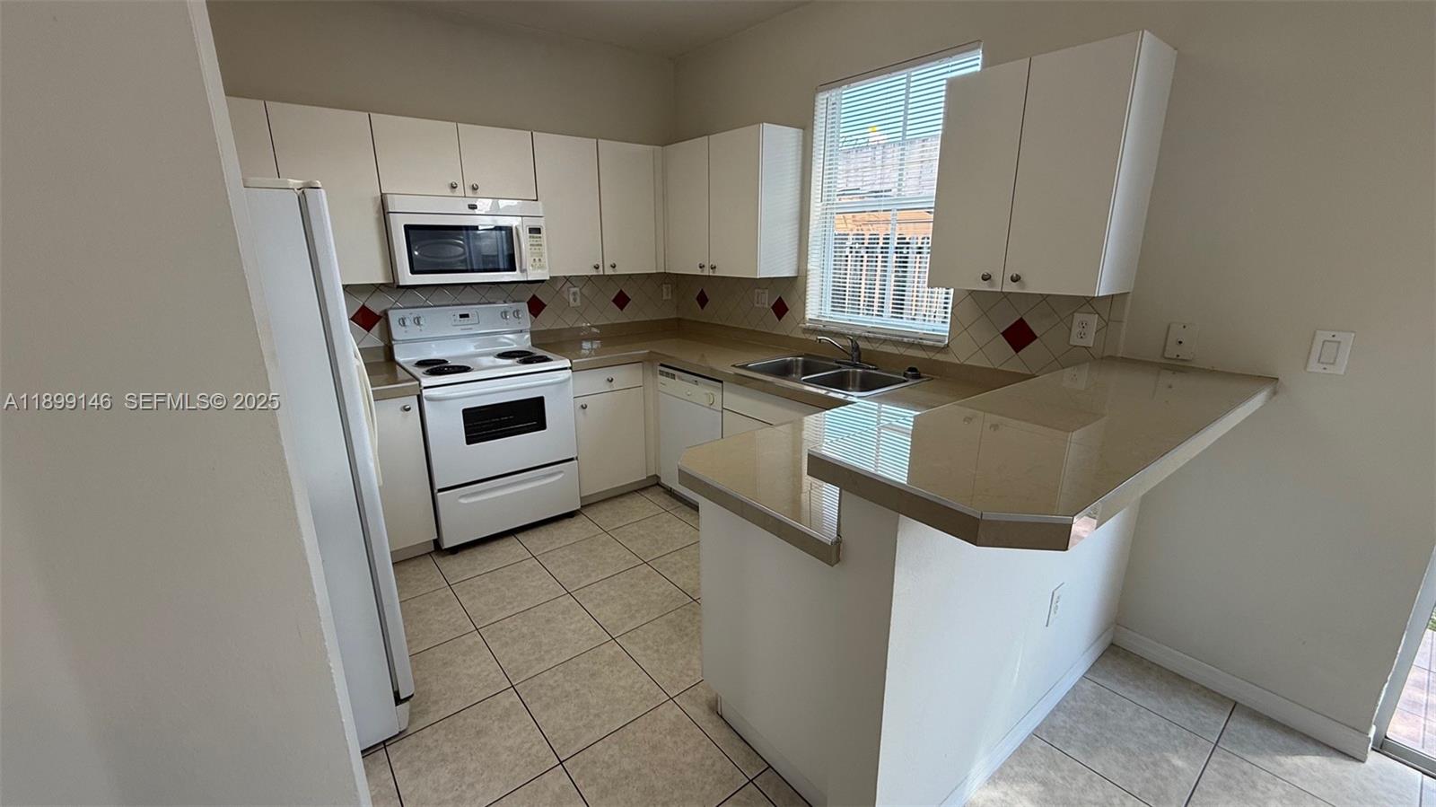 13810 Southwest 276th Street, Unit 13810 Homestead, FL 33032 - Photo 11 of 38 a kitchen with a stove a sink and a microwave