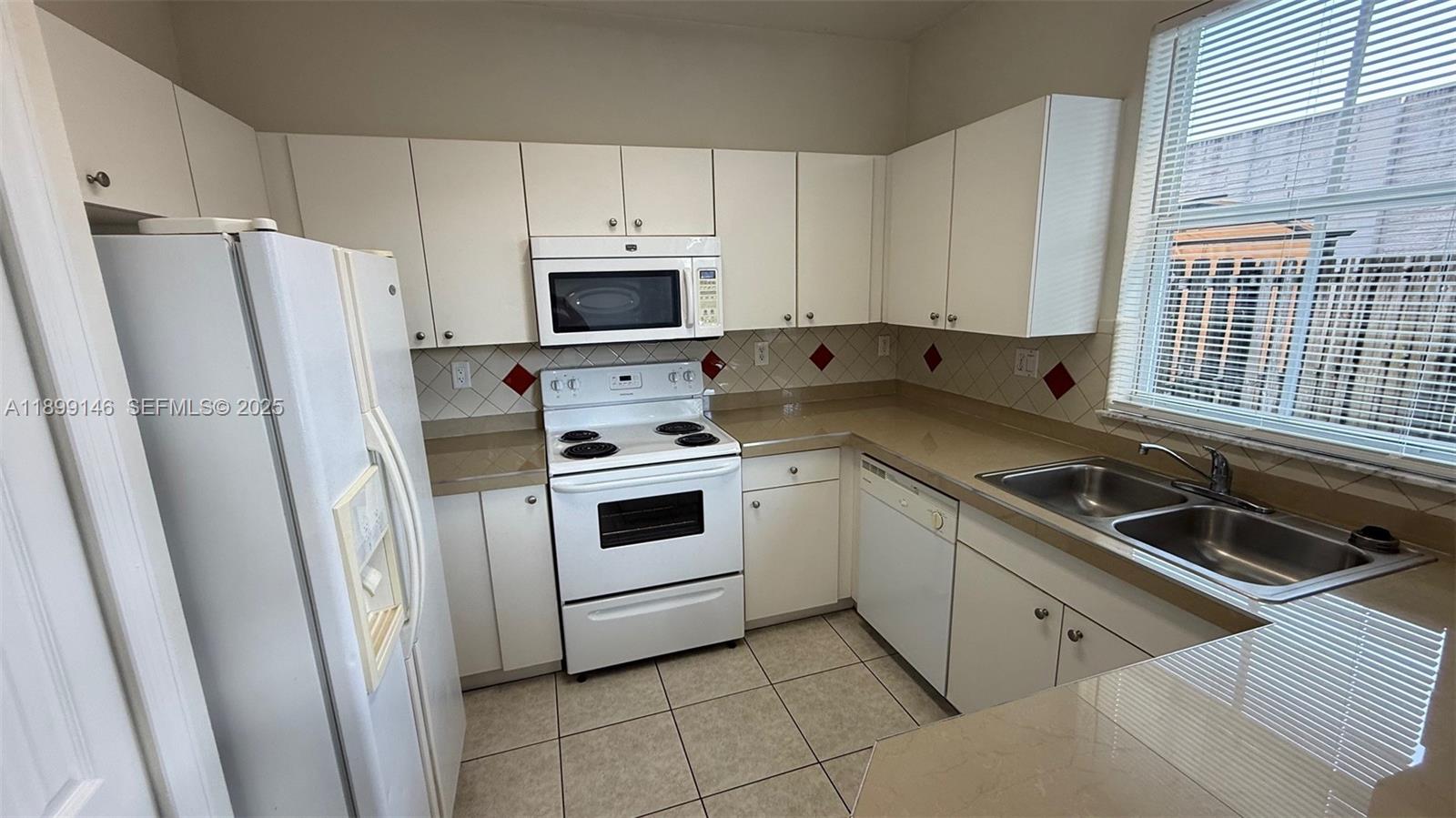 13810 Southwest 276th Street, Unit 13810 Homestead, FL 33032 - Photo 12 of 38 a kitchen with white cabinets and white appliances