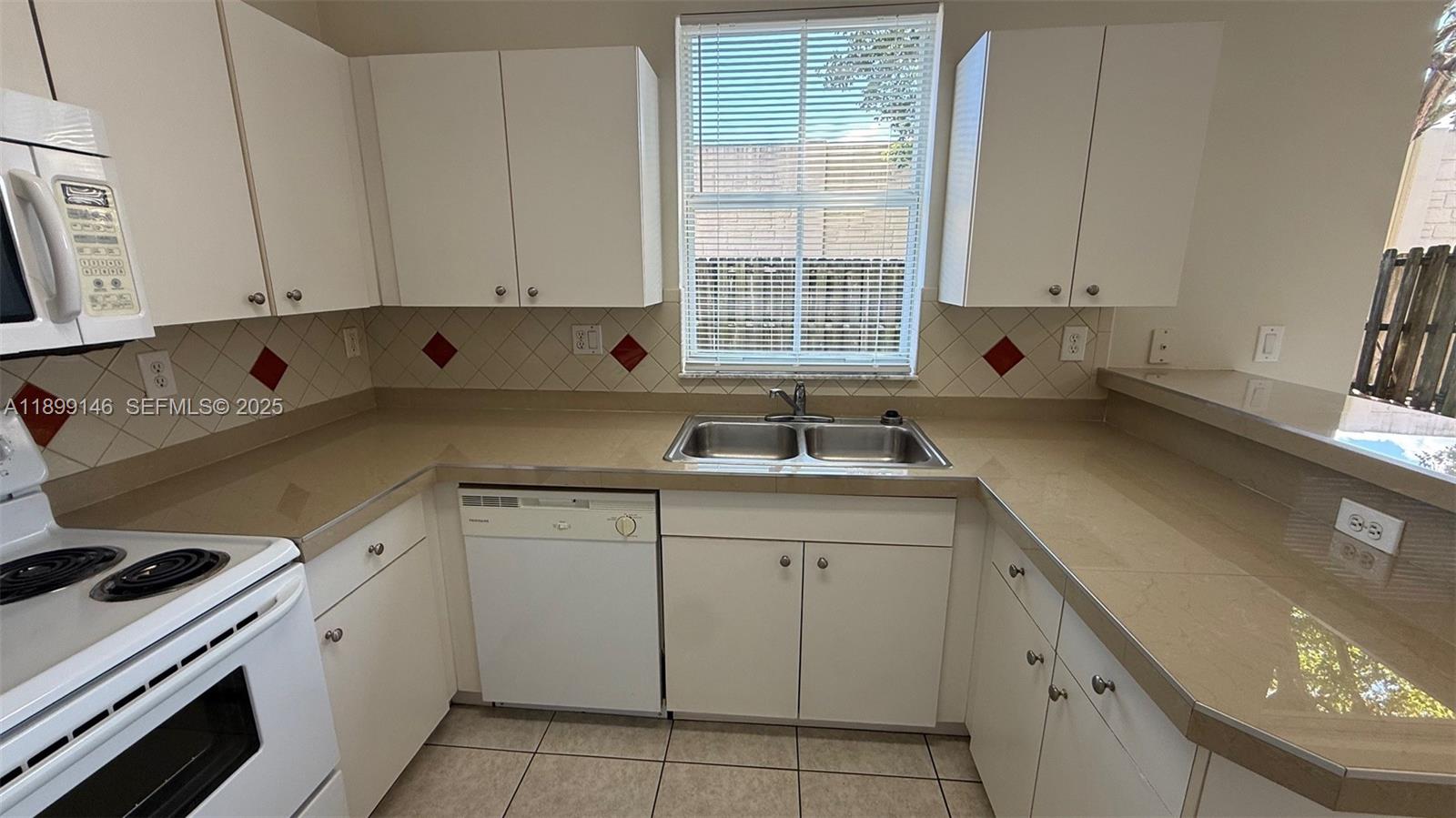 13810 Southwest 276th Street, Unit 13810 Homestead, FL 33032 - Photo 13 of 38 a kitchen with cabinets appliances a sink and a window