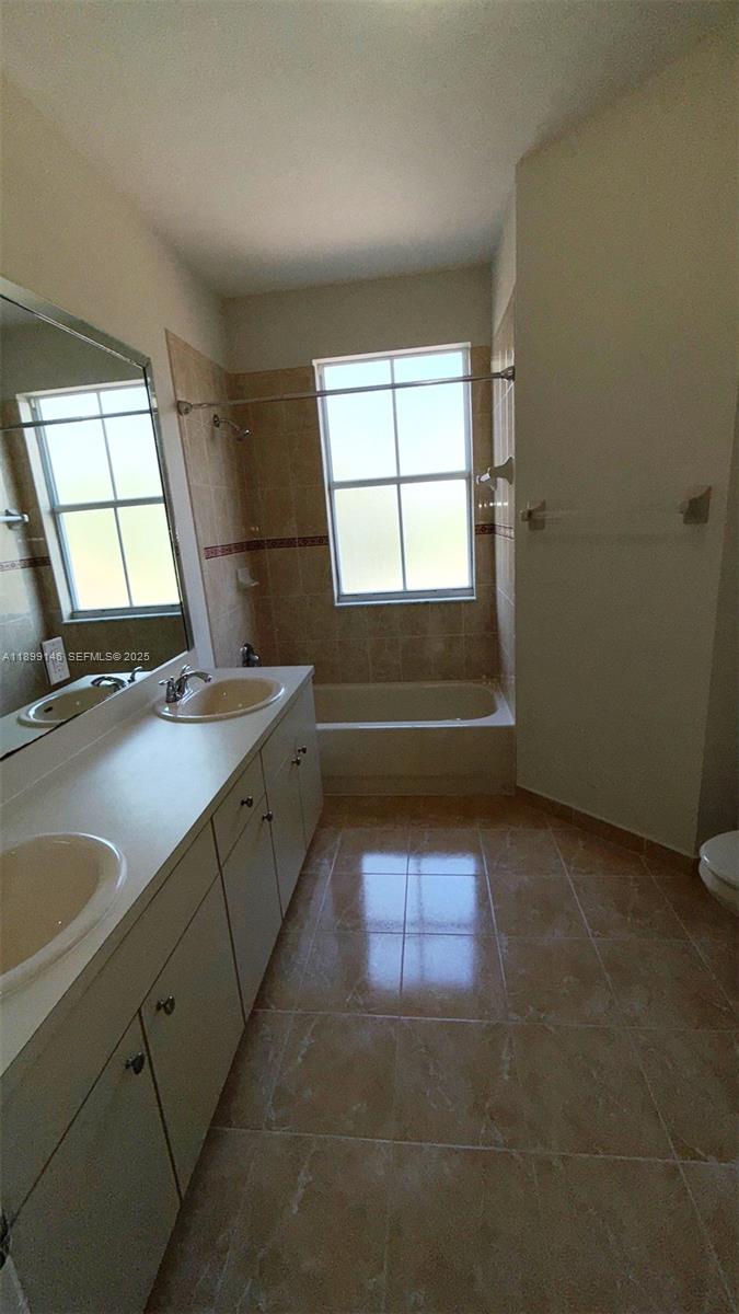 13810 Southwest 276th Street, Unit 13810 Homestead, FL 33032 - Photo 23 of 38 a bathroom with a sink a bathtub and next to a window