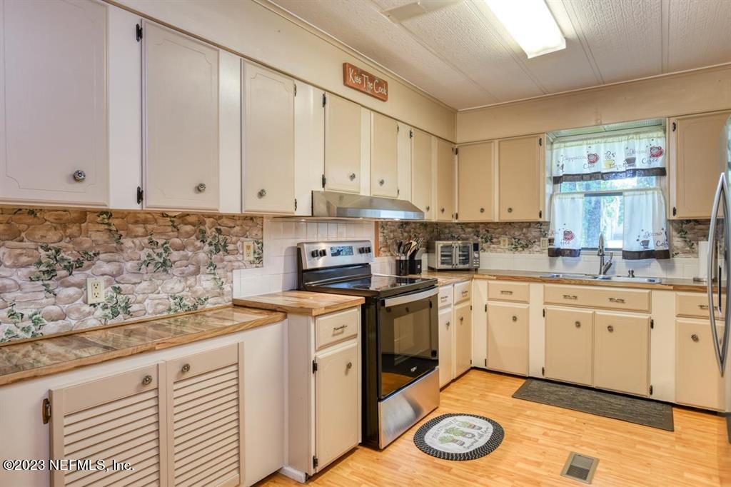 2221 Twin Fox Trail St. Augustine, FL 32086 - Photo 13 of 36 a kitchen with stainless steel appliances granite countertop a sink a stove cabinets and a window