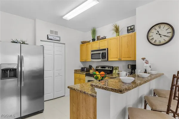 a kitchen with stainless steel appliances granite countertop a refrigerator a stove and a sink