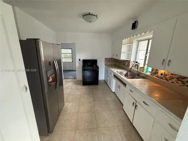 a large kitchen with a stove a refrigerator a sink dishwasher and wooden cabinets