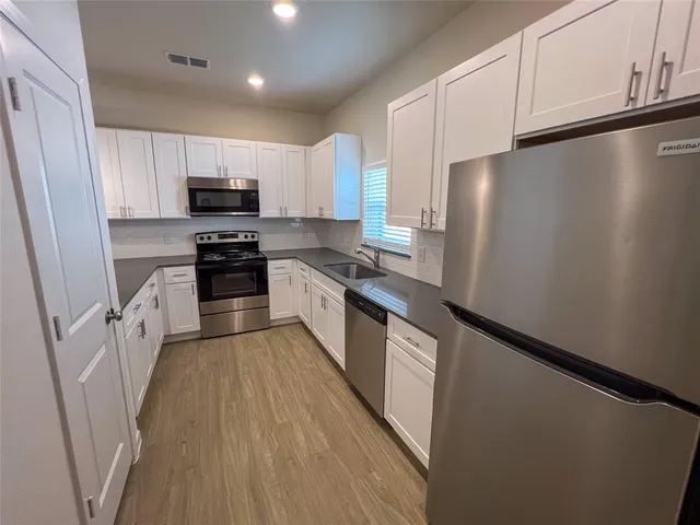 a large kitchen with stainless steel appliances sink a microwave and cabinets