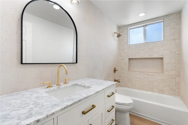a bathroom with a granite countertop toilet a sink and a mirror